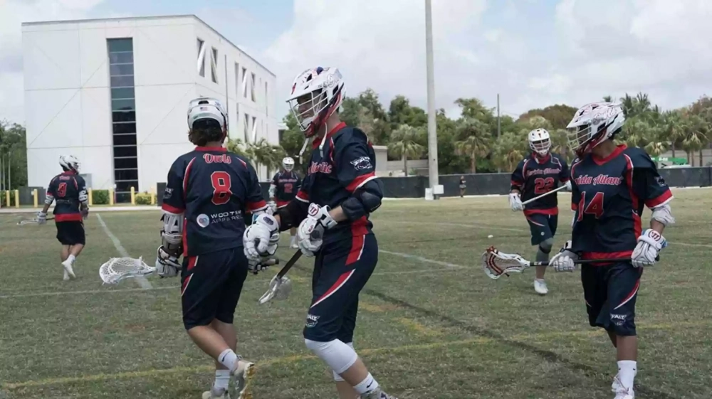 Lacrosse players wearing custom lacrosse uniforms on lacrosse field.