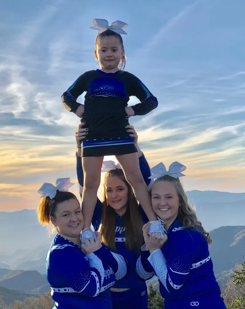 Cheer Leaders holding cheerleader straight wearing custom personalized cheer uniforms