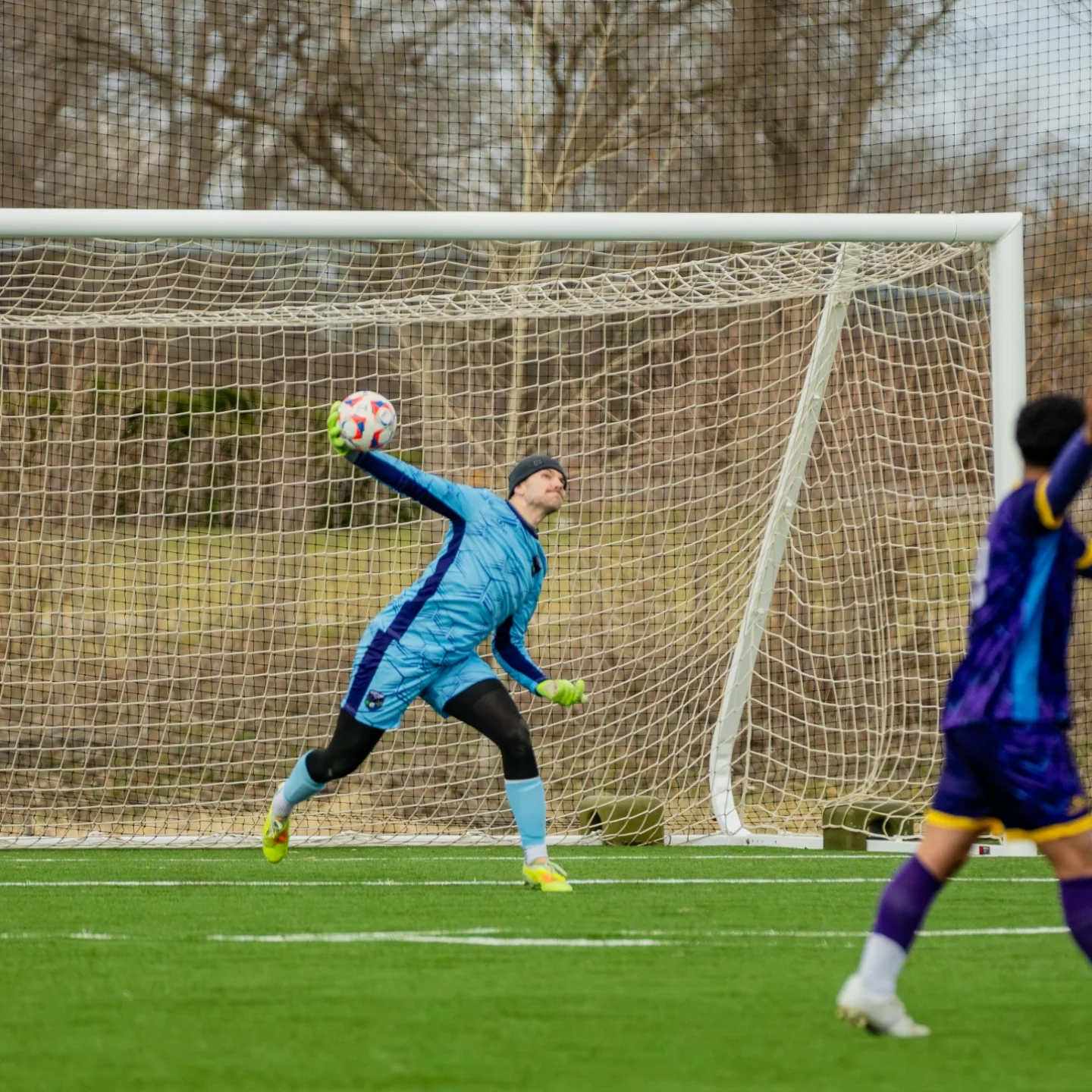 Goalkeeper wearing custom crew neck goalie soccer jersey making a save