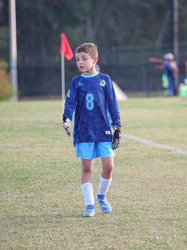 Young goalkeeper wearing blue custom crew neck goalie soccer jersey