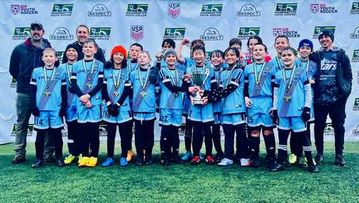 Youth soccer team wearing custom blue uniforms and custom soccer shorts on grass field