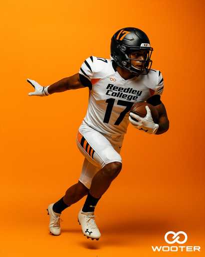 Youth football player wearing custom football gloves on orange background