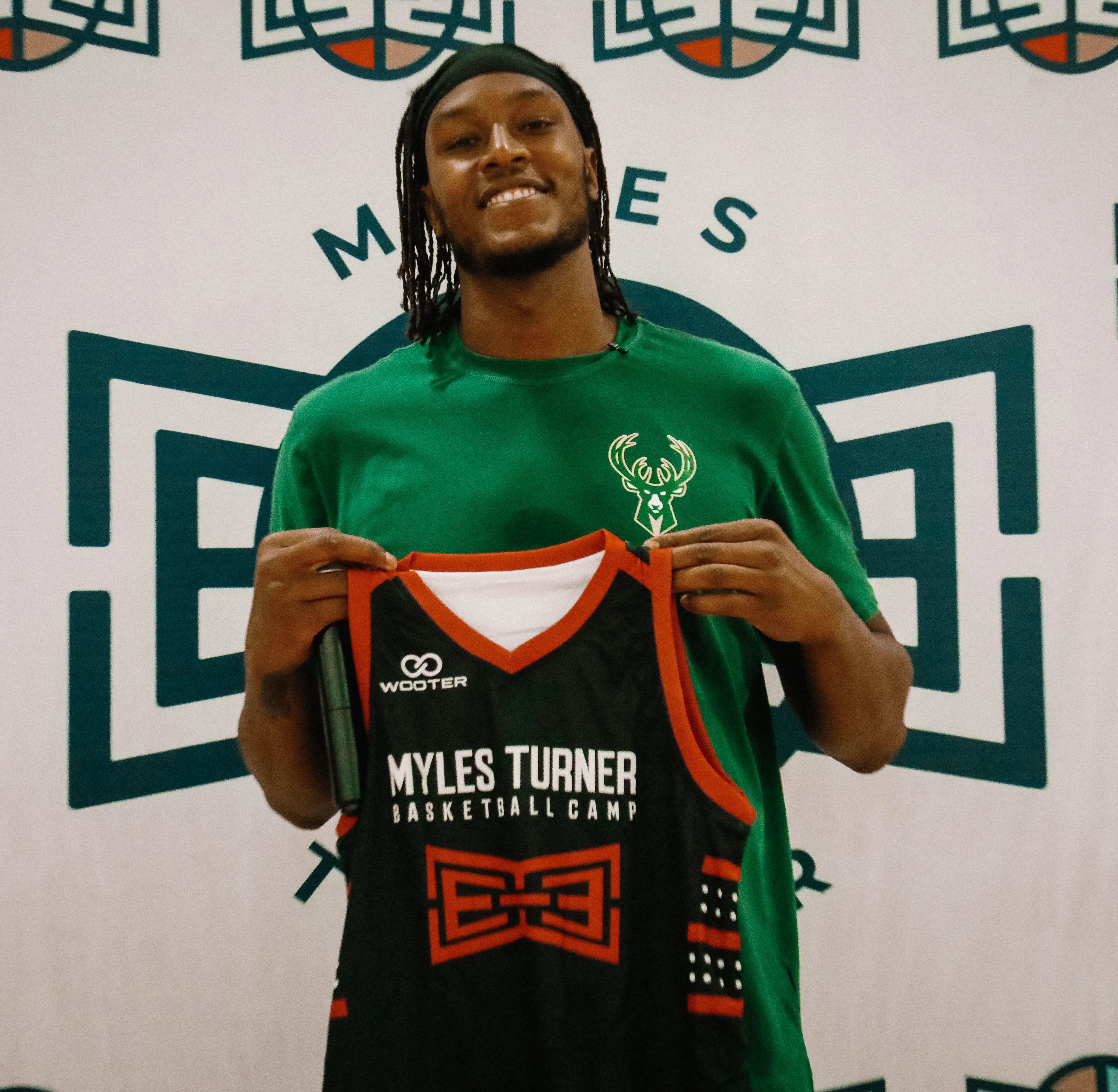 Myles Turner from Milwaukee Bucks at Myles Turner Basketball Camp. Myles turner holding custom basketball jersey for Myles Turner camp from Wooter Apparel.